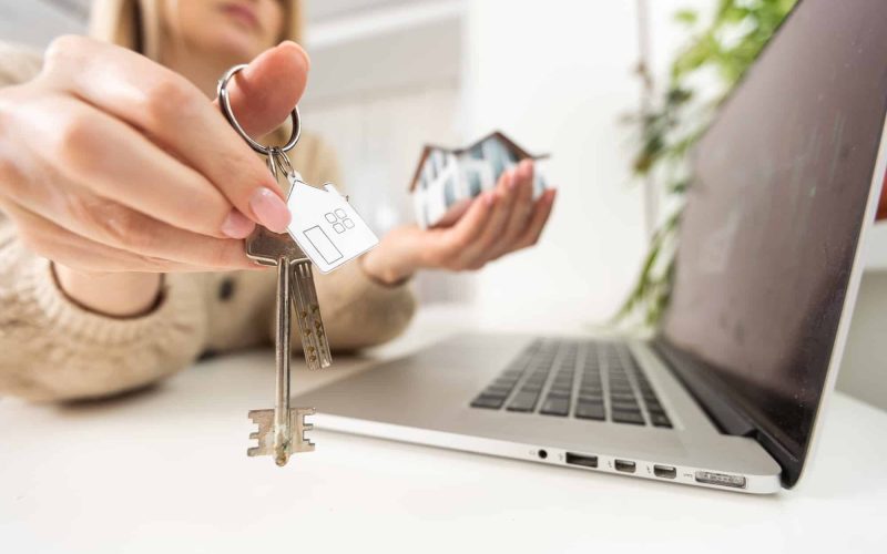 Woman holding keys with laptop